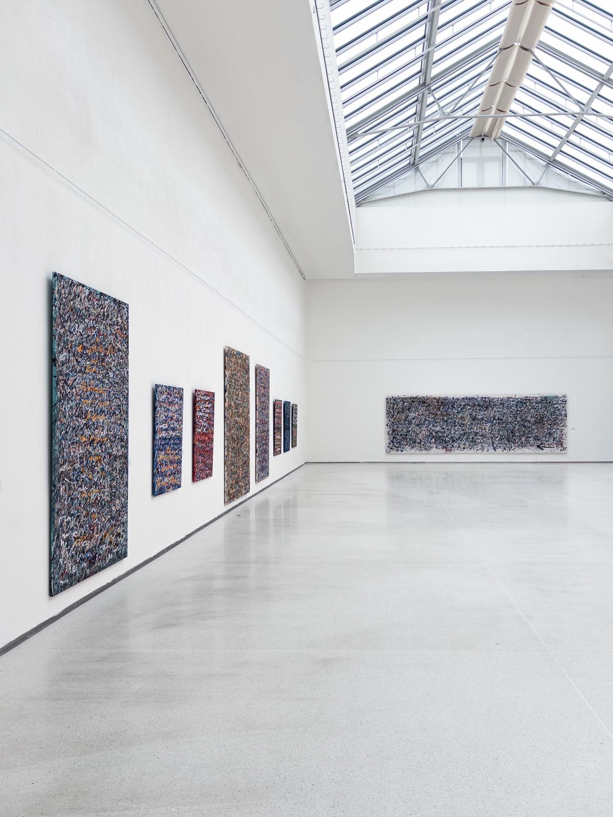 Anima Mundi paintings extending through the skylit gallery at Mánes